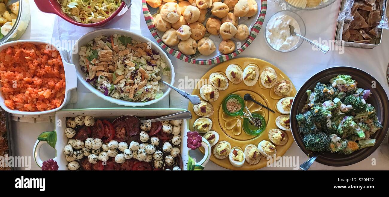 A panoramic view of a veritable feast featuring deviled eggs, salads and desserts  on top of a crisp white tablecloth. Stock Photo