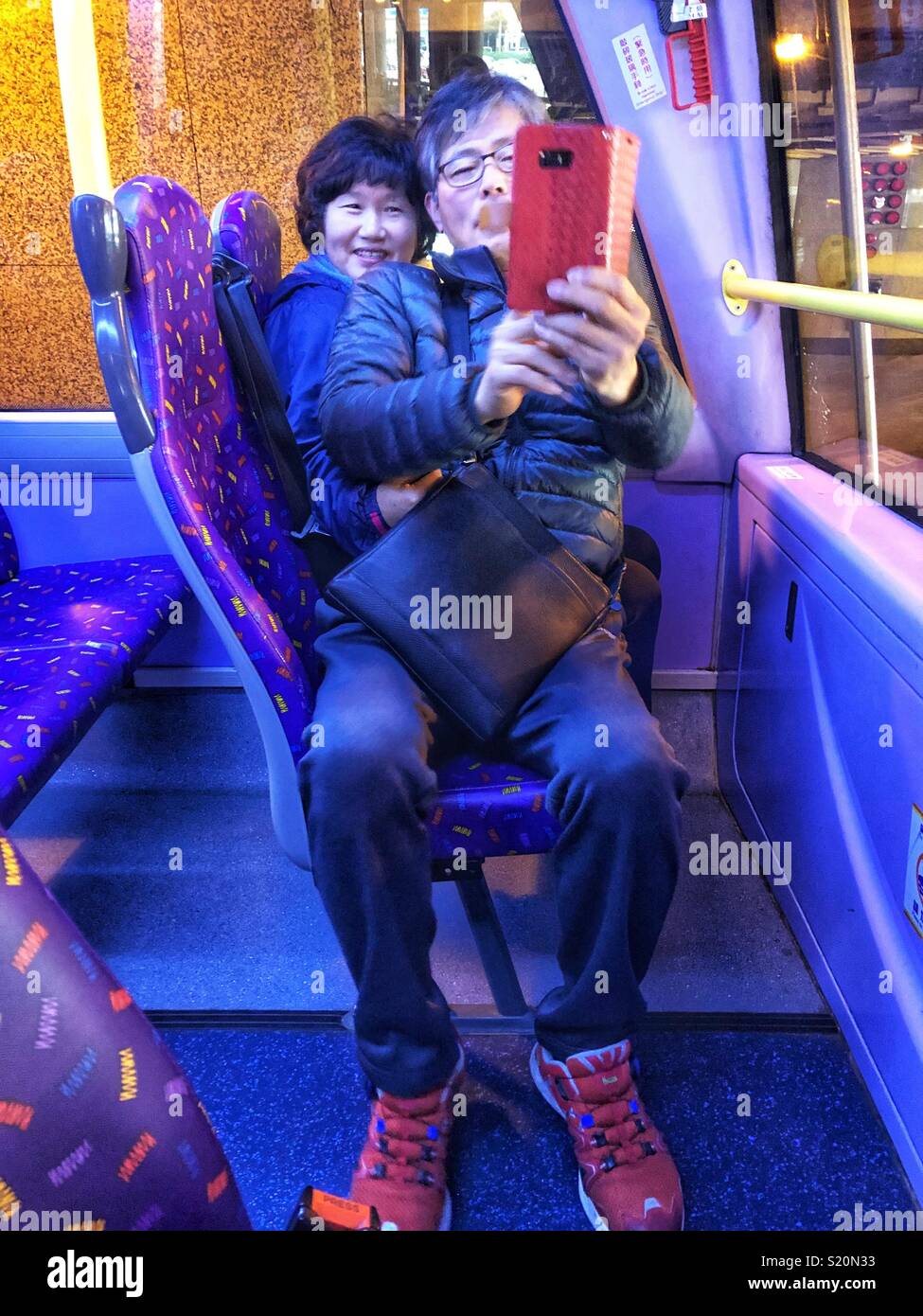 Asian tourists take a selfie on a public bus in Hong Kong. - Smartphone Captured Stock Image