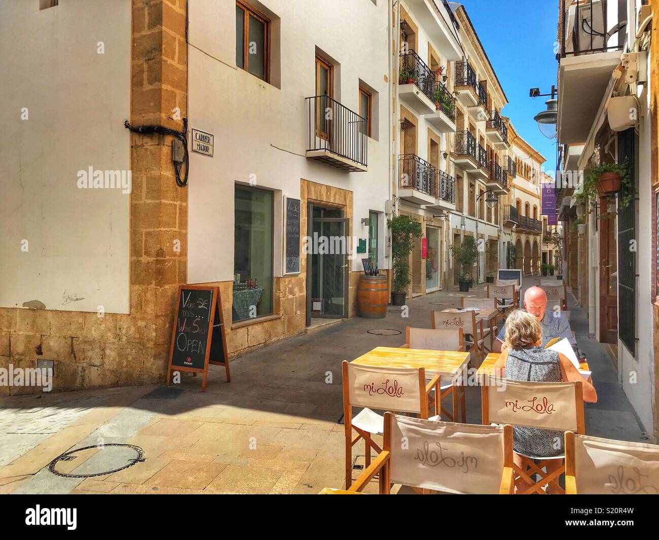 Street scene with senior couple at outdoor cafe, in the Old Town area of Javea / Xabia on the Costa Blanca, Spain - Smartphone Captured Stock Image