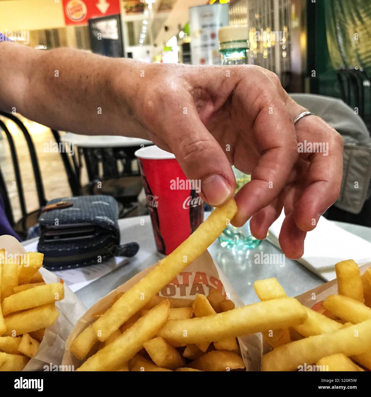 Woman eating French fries whilst waiting for a delayed flight in the departures area of El Altet airport, Alicante, Spain Stock Photo