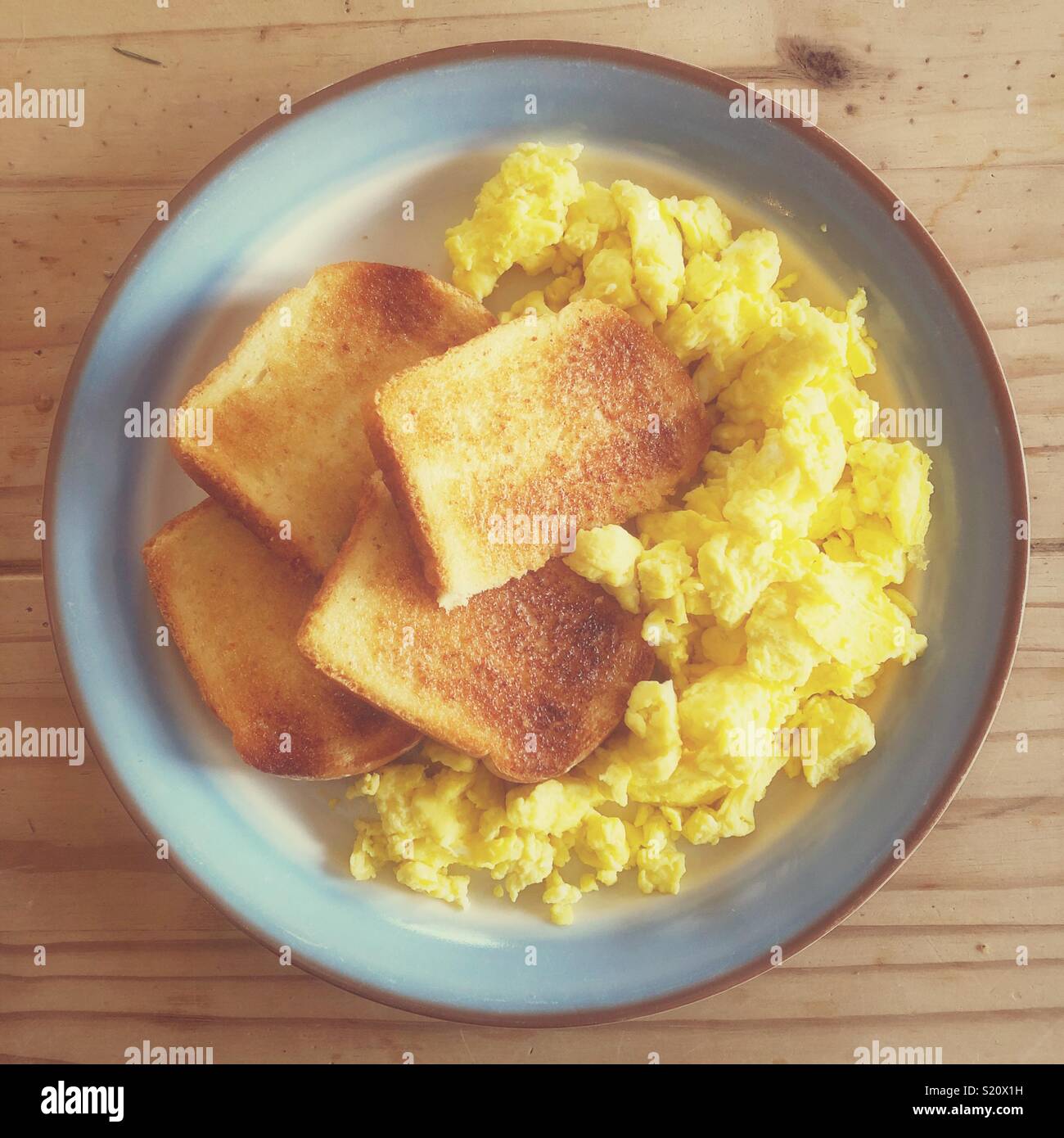 Scrambled eggs and toast on a plate in warm morning light - Smartphone Captured Stock Image