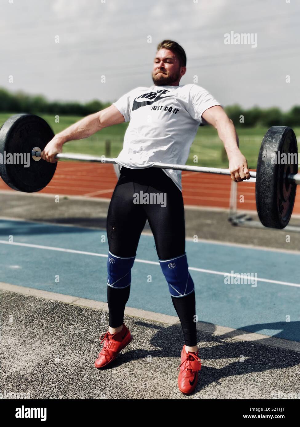 Olympic Weightlifter performing a snatch on an athletics track. Stock Photo