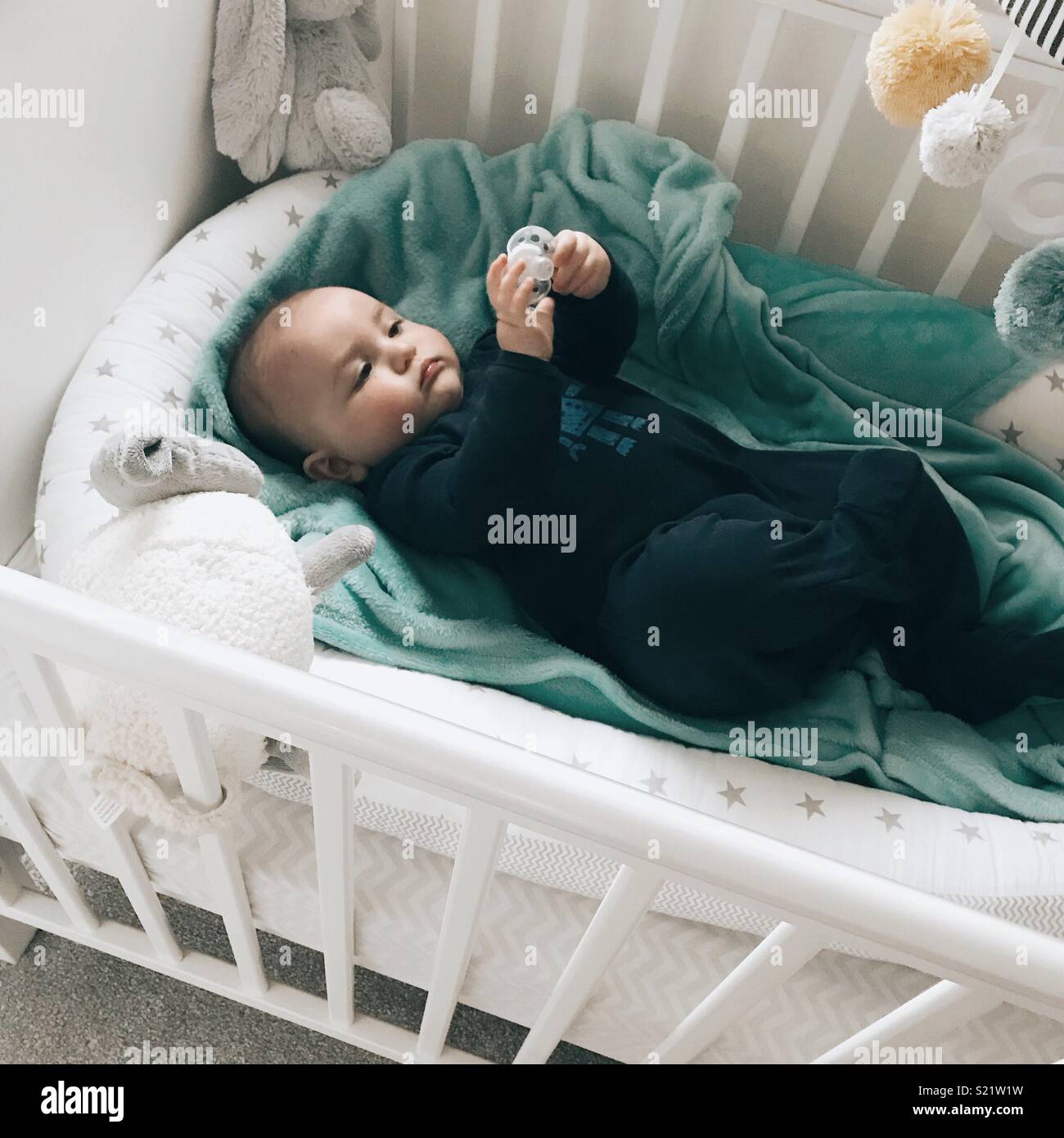 Baby boy laying in a cot Stock Photo
