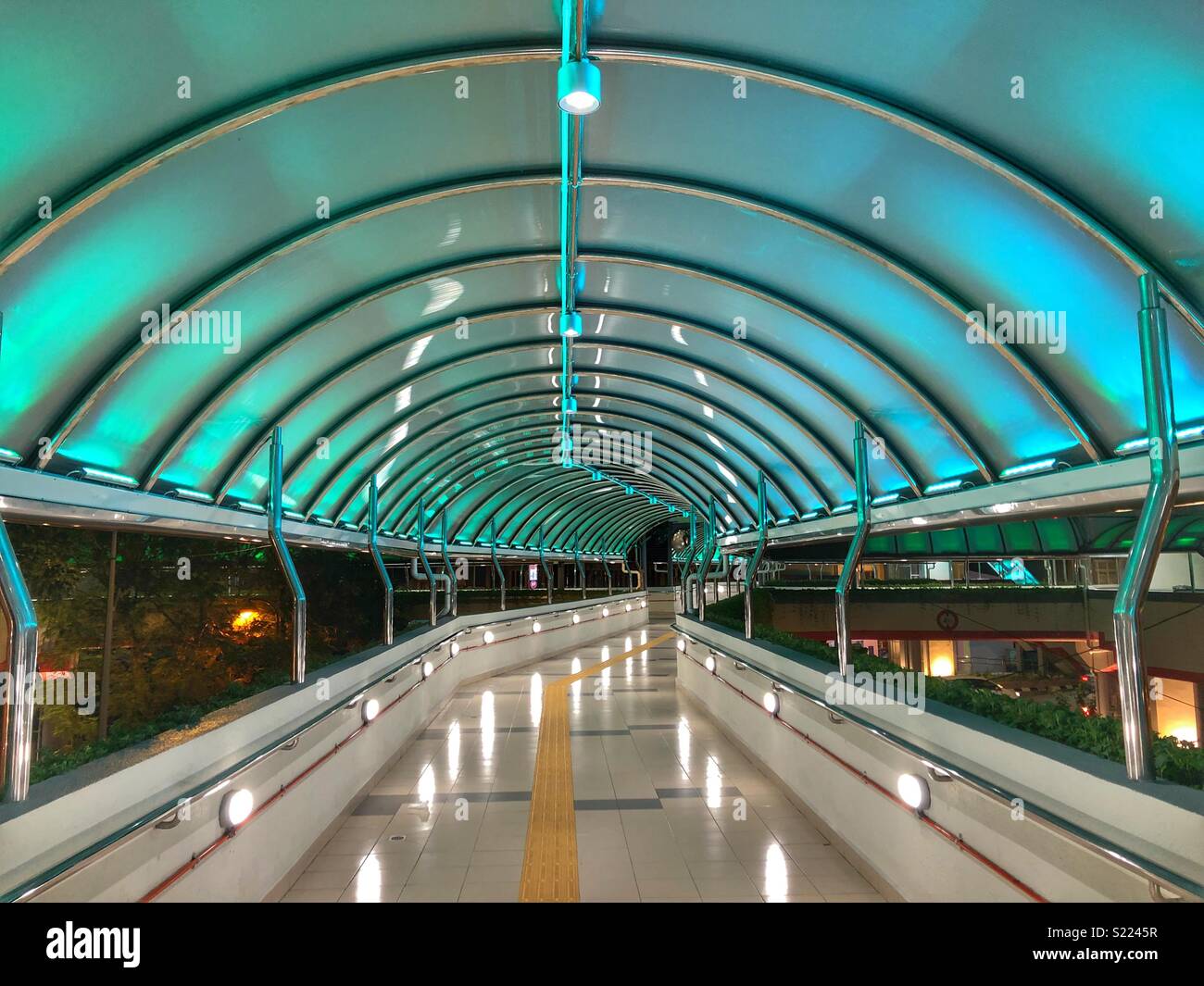 Covered pedestrian bridge illuminated in blue. - Smartphone Captured Stock Image