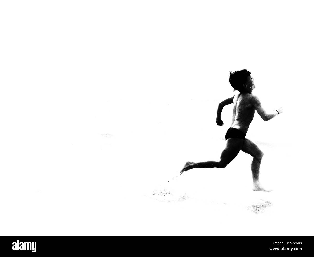 Boy running on the beach. Runner silhouetted on black and white Stock Photo