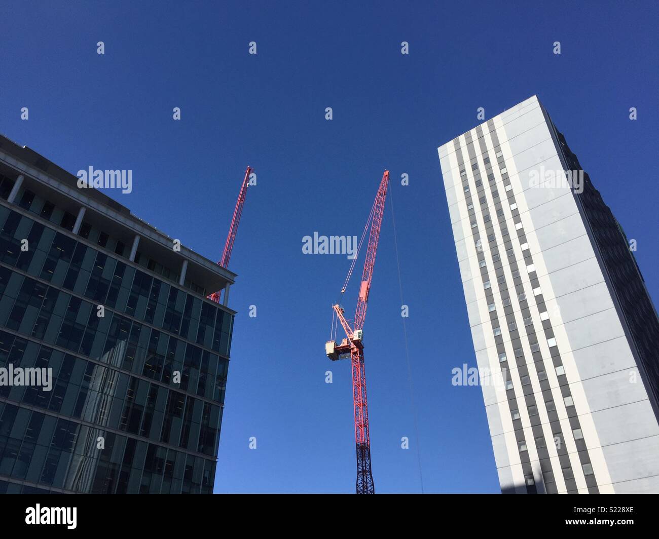 Construction crane and buildings against a blue sky. - Smartphone Captured Stock Image
