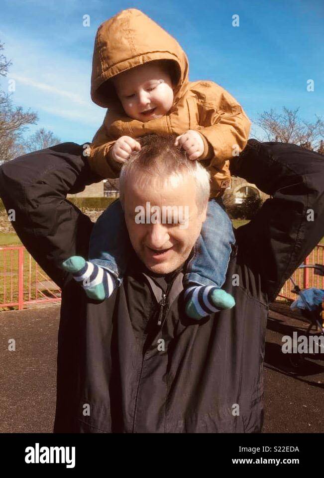 Toddler on grandad’s shoulders Stock Photo