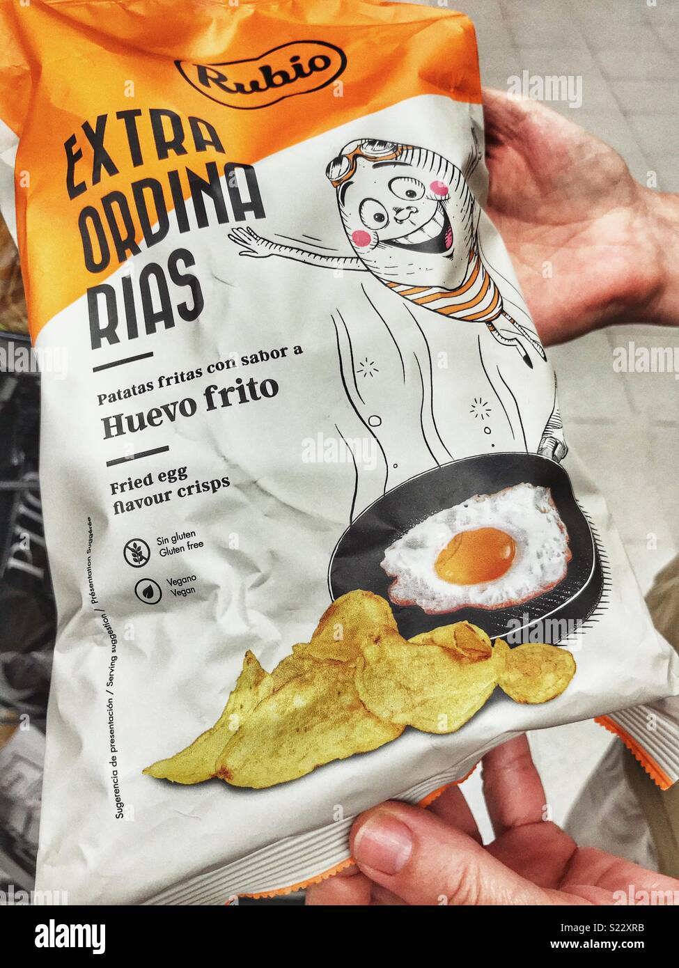Woman holding a bag of Fried egg flavour crisps in a Spanish supermarket Stock Photo