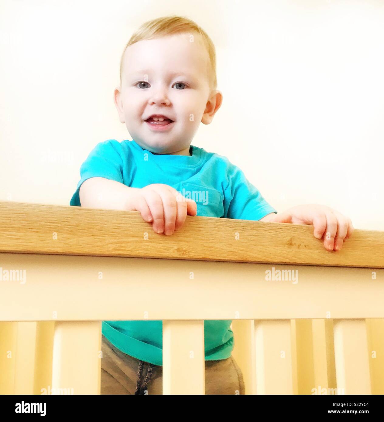 Toddler standing in cot Stock Photo Alamy