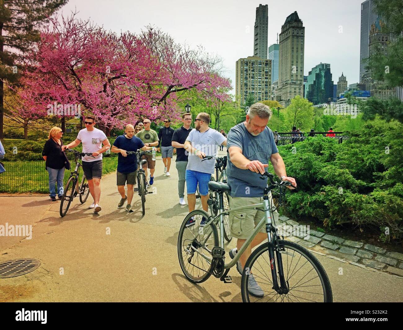 Cyclists walking their bikes on a path on a spring day in Central Park, NYC, USA - Smartphone Captured Stock Image