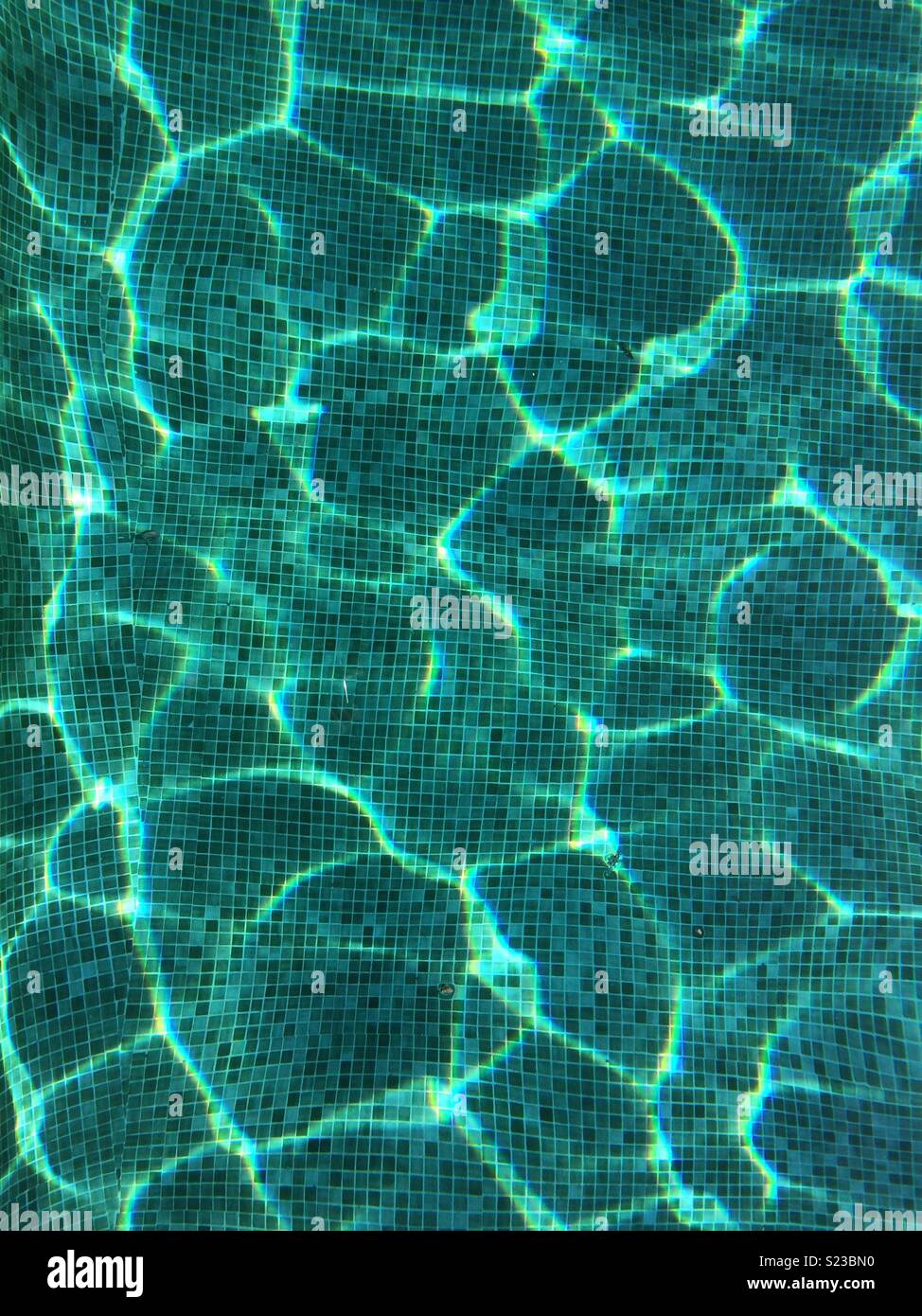 Abstract pattern created by sun light through water in mosaic swimming pool. A palette of blues and greens form in to beautiful, calming patterns. - Smartphone Captured Stock Image