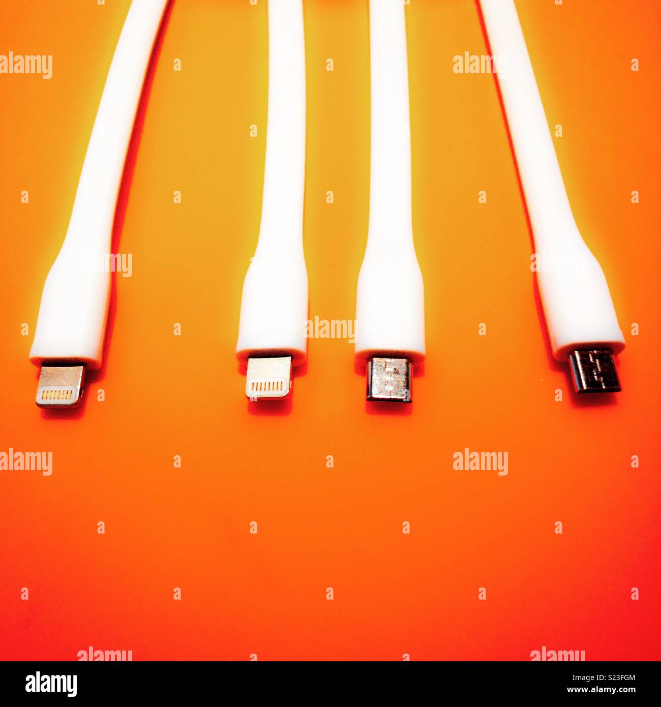 Phone charging cables on an orange mat Stock Photo