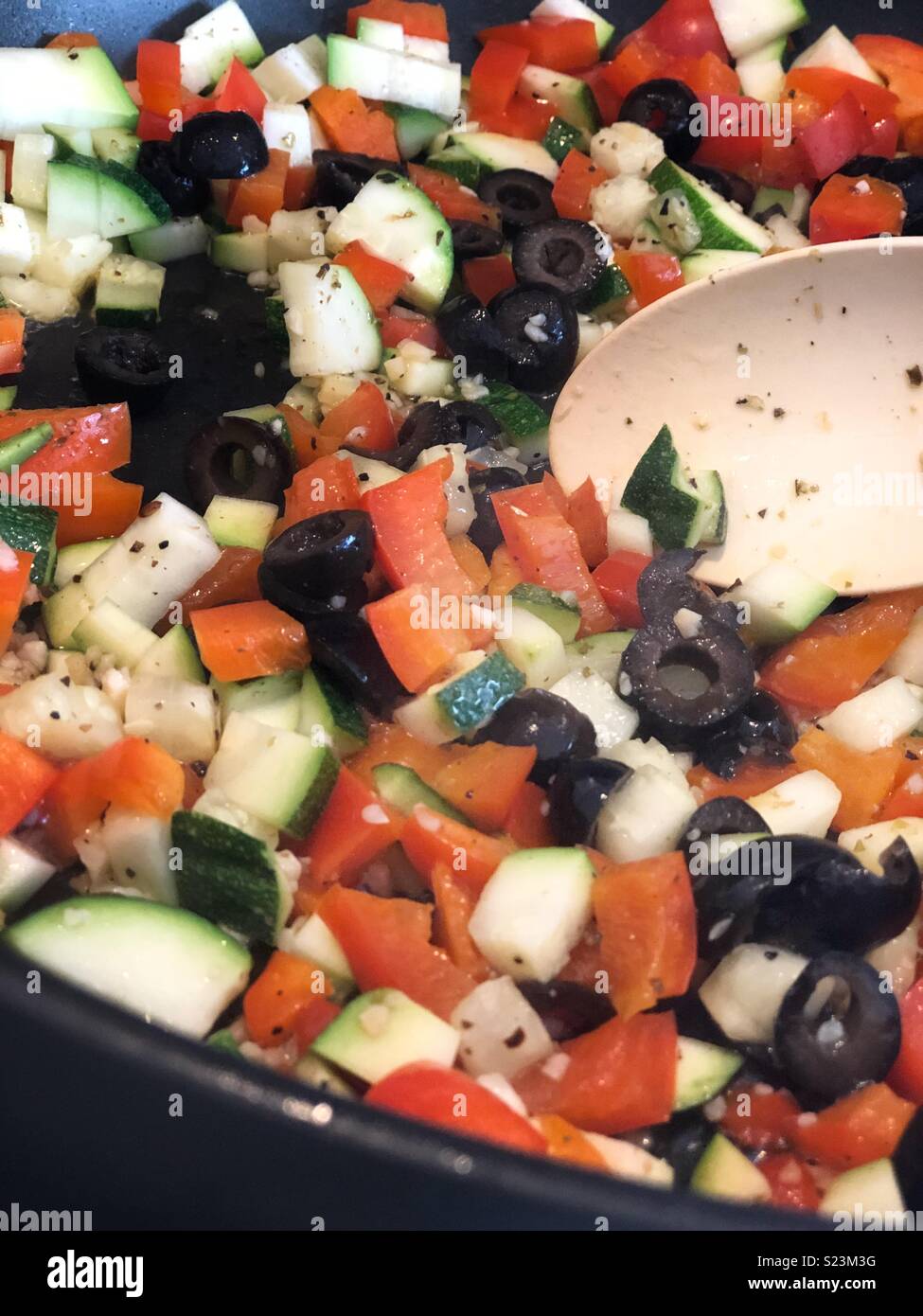 Red bell peppers, black olives and zucchini being sautéed in a skillet - Smartphone Captured Stock Image