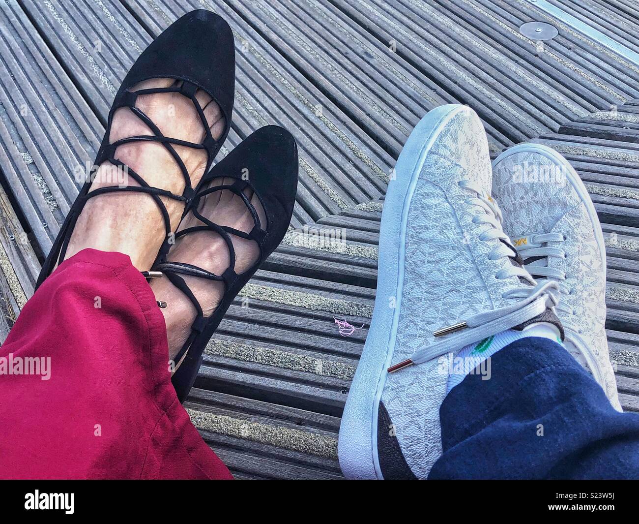 Two pairs of women's feet wearing different styles of shoe. - Smartphone Captured Stock Image
