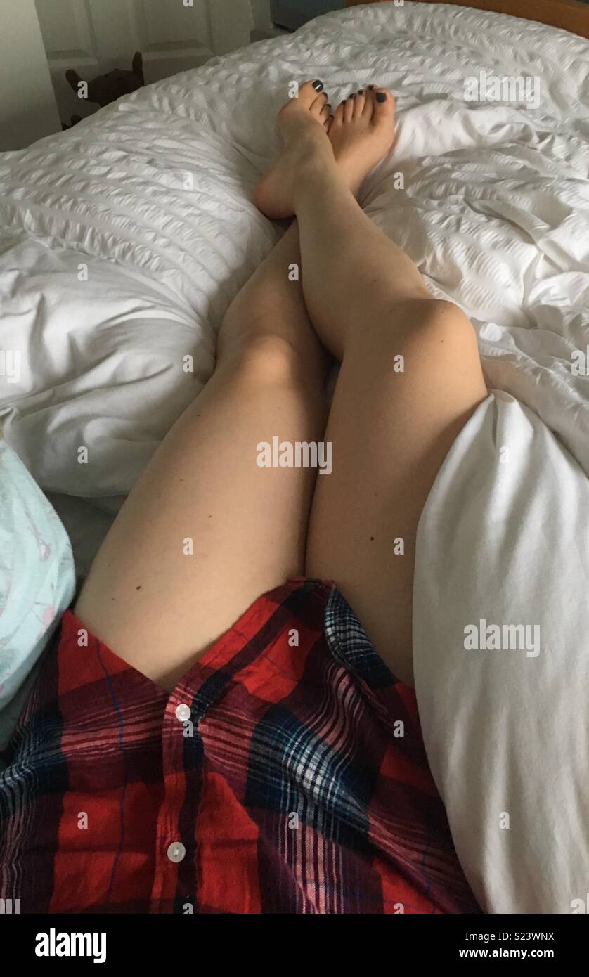 Woman’s legs in bed Stock Photo