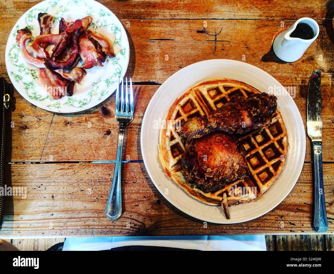 Waffle with fried chicken for breakfast. Side of maple cured bacon and some maple syrup Stock Photo