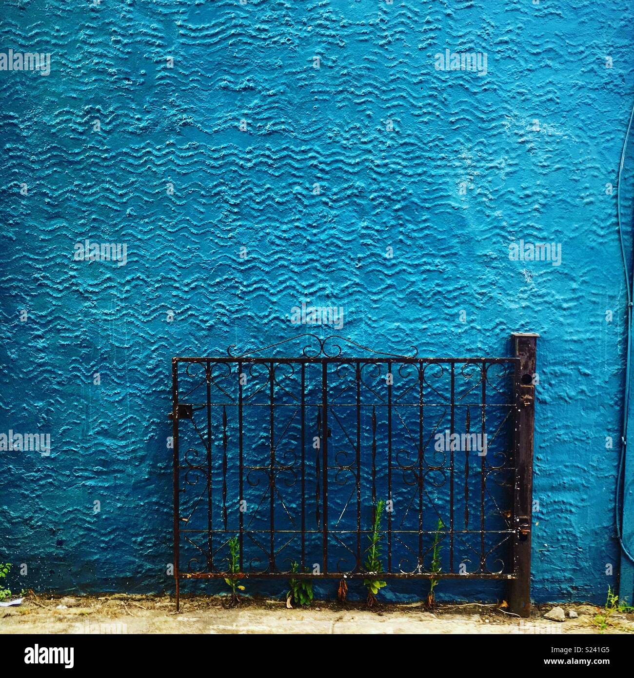 Turquoise textured wall and black gate to nowhere Stock Photo