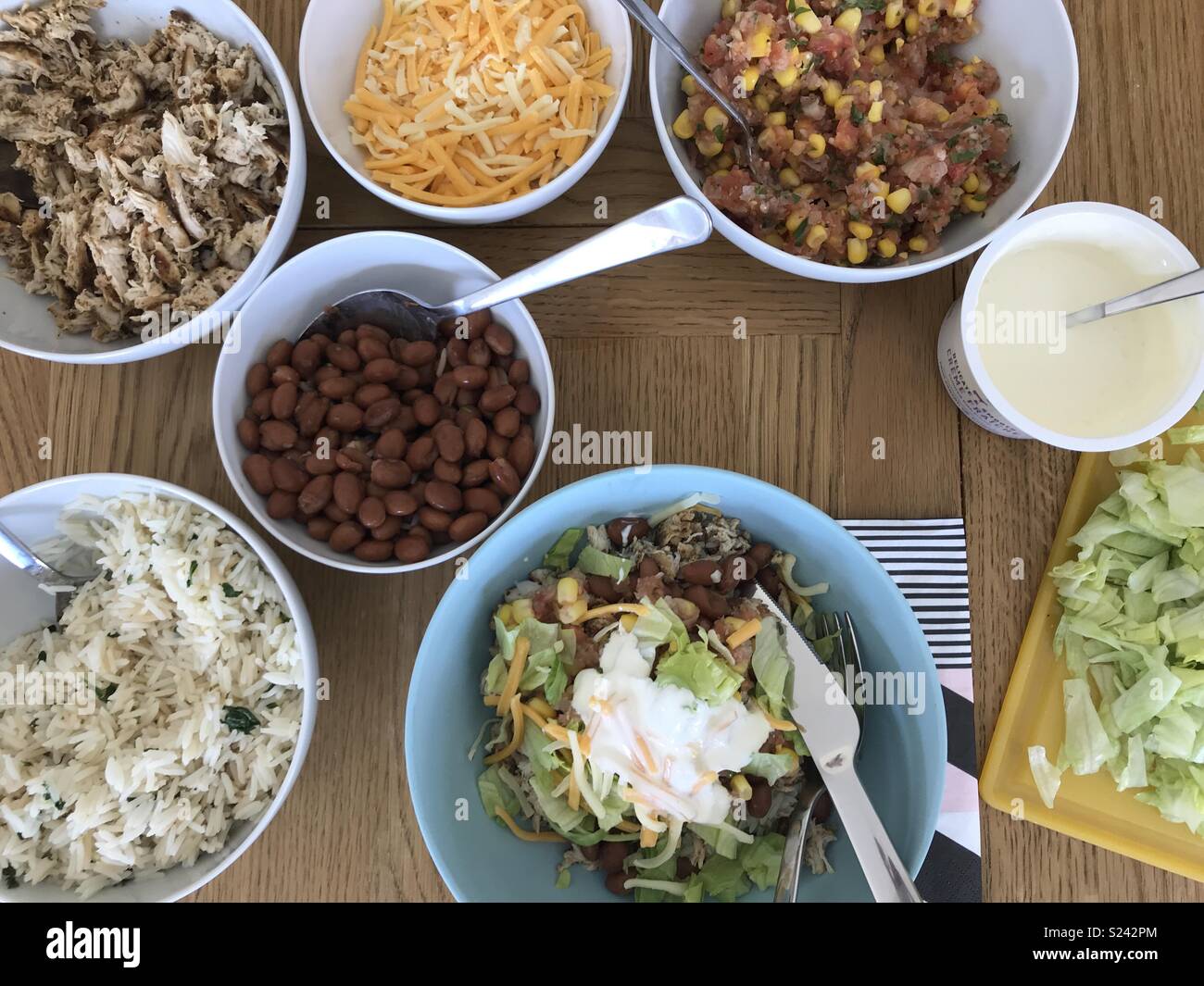 A spread of ingredients to make a spicy chicken burrito bowl at home Stock Photo
