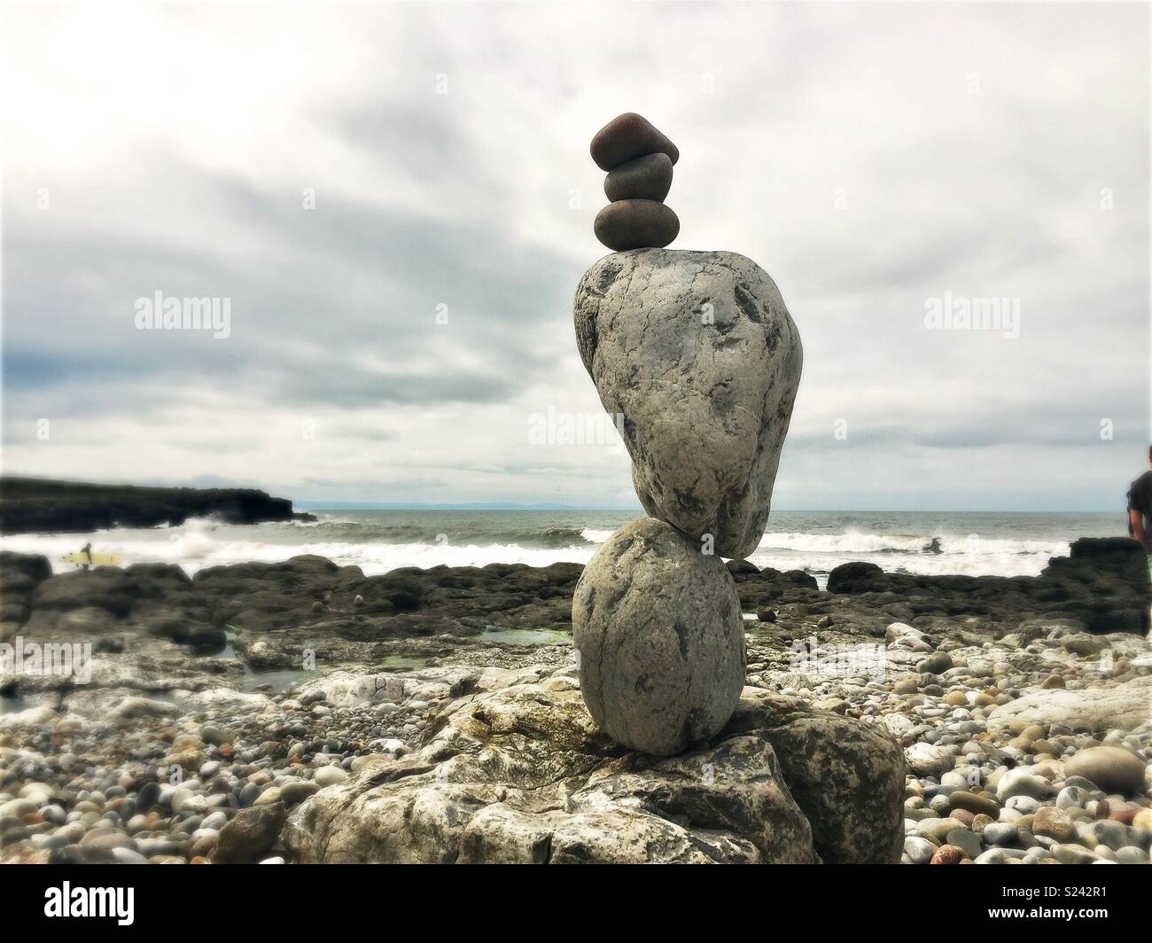 Natural stone balancing sculpture on beach with waves. Stock Photo