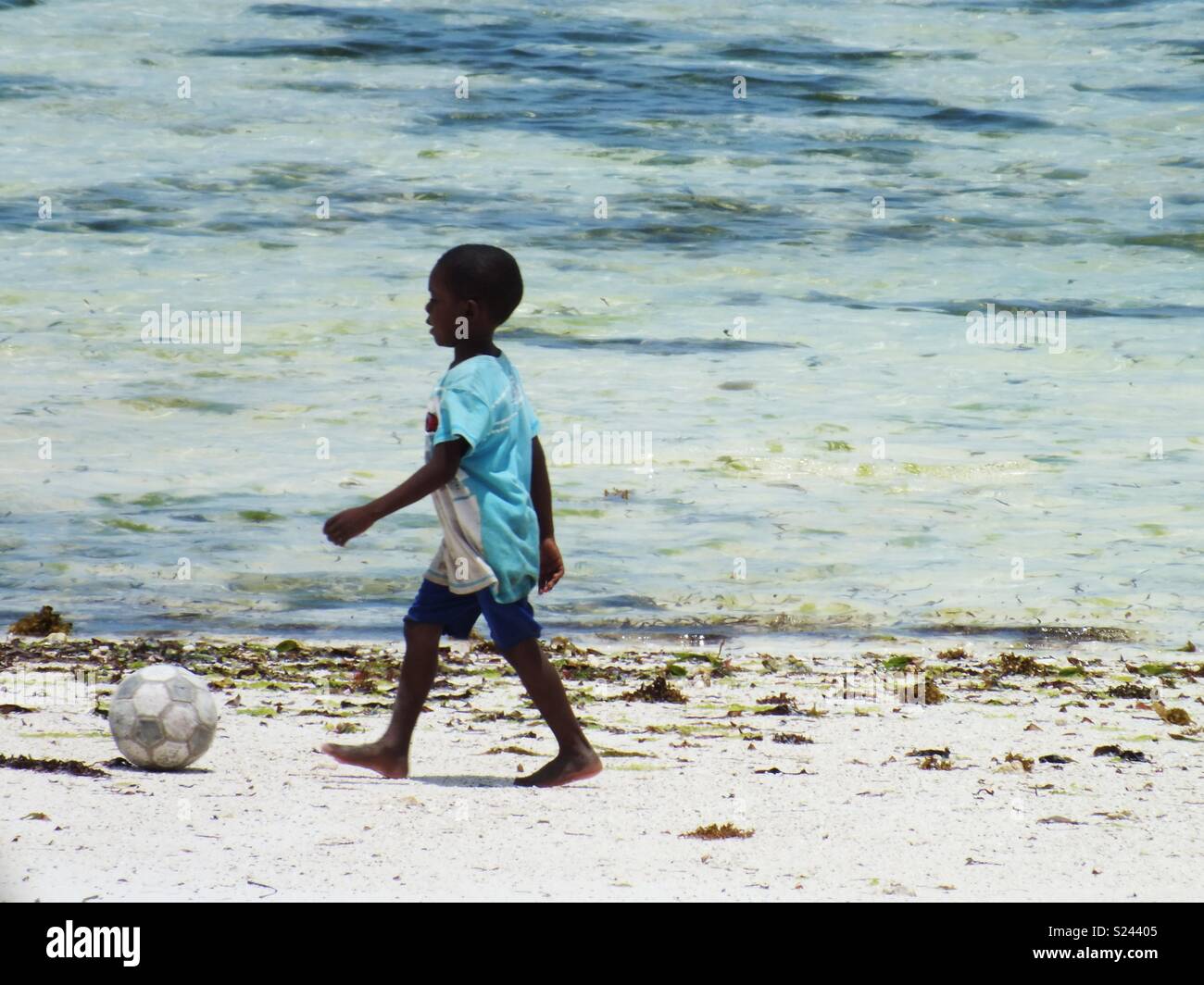 Boy kicking football along the beach. Zanzibar, Tanzania. Stock Photo