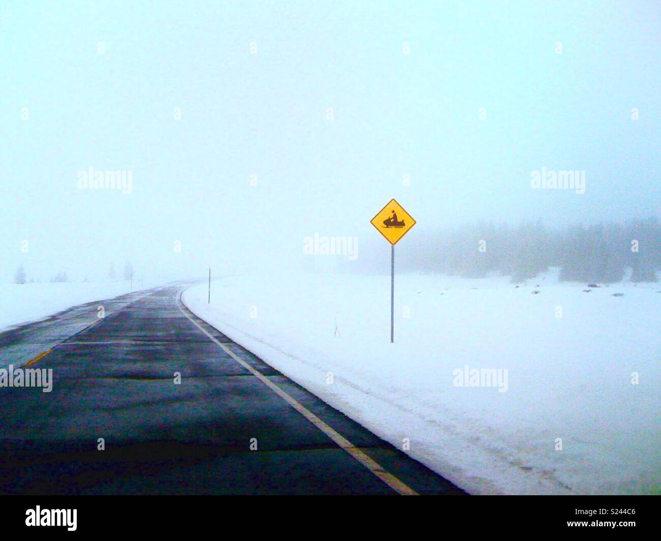 Snowmobile sign on empty road in the winter. - Smartphone Captured Stock Image