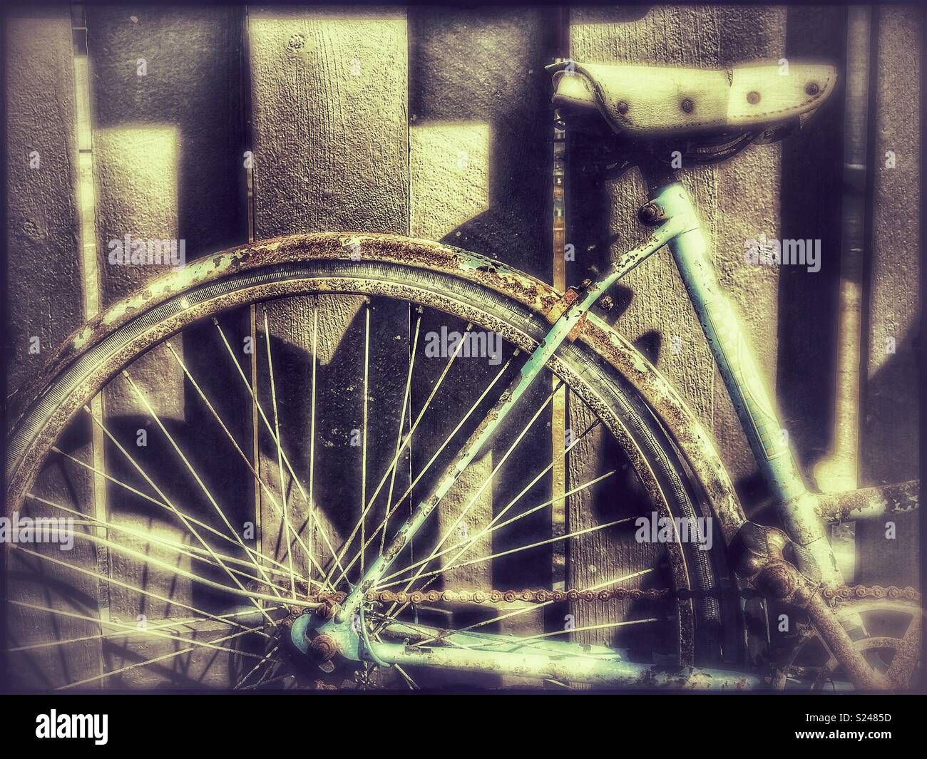 Rusty old bicycle parked against a wooden fence Stock Photo