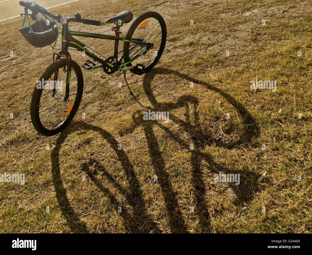 Bicycle with helmet in sunshine on grass with long shadows - Smartphone Captured Stock Image