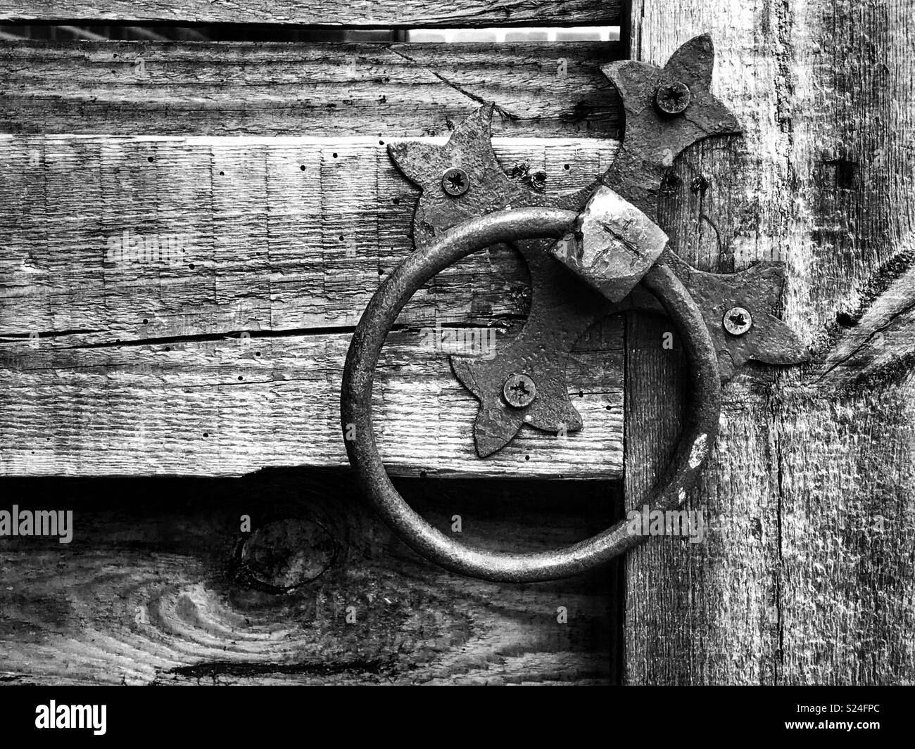 Old metal door knocker handle on barn door in monochrome. - Smartphone Captured Stock Image
