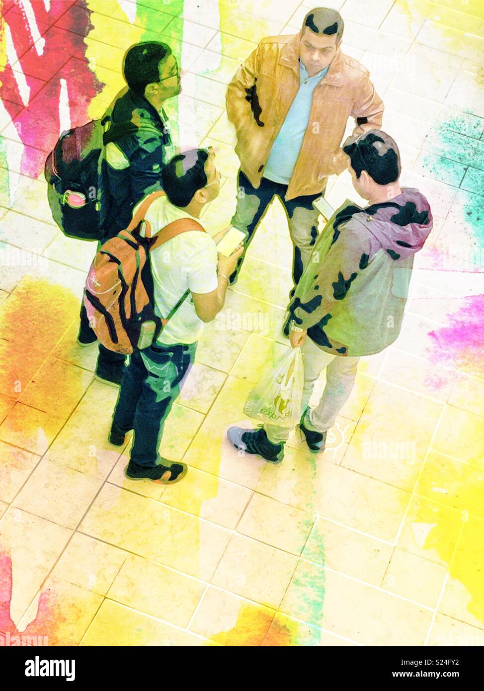 Four men waiting on their train and checking their smartphones - Smartphone Captured Stock Image