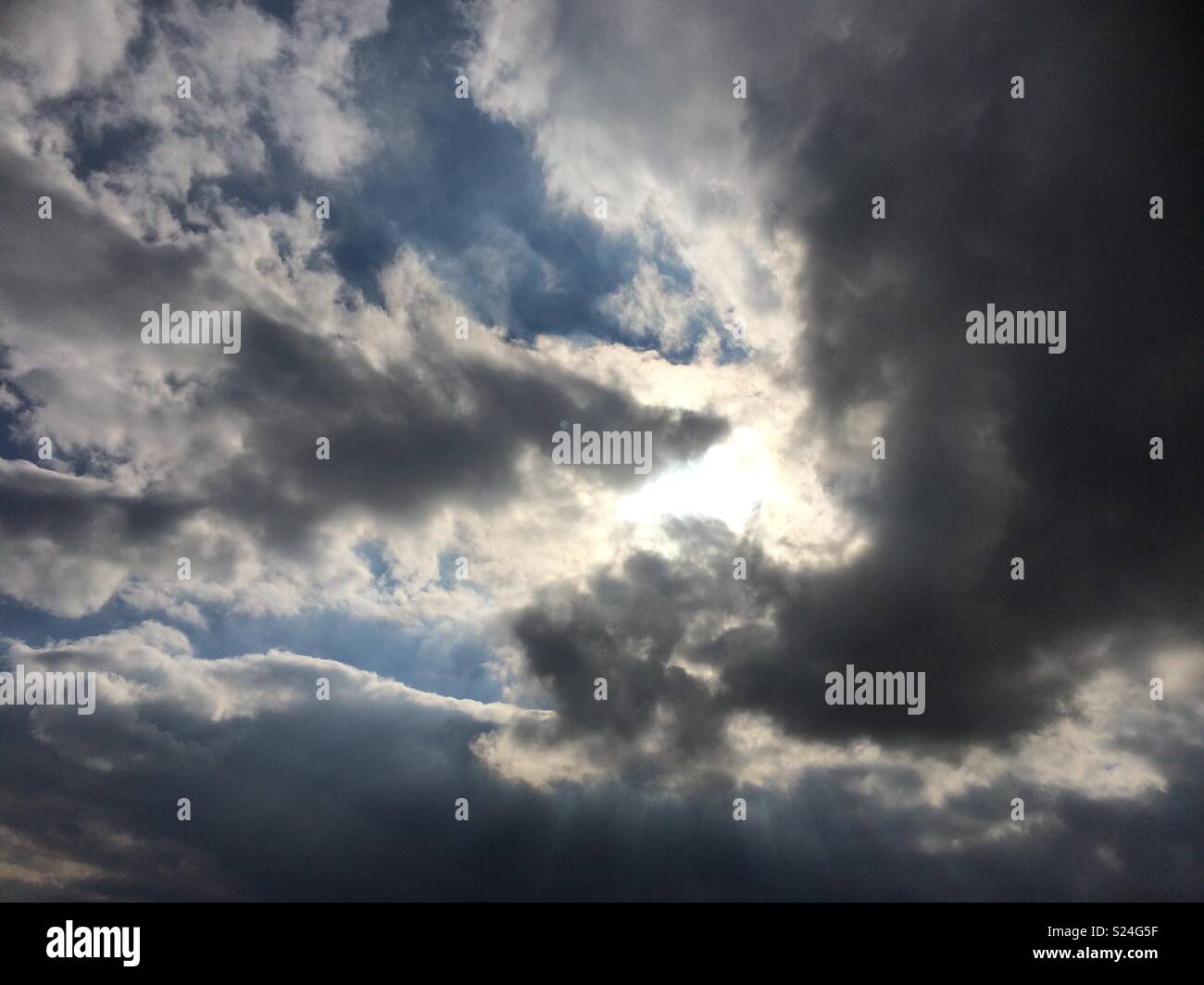 Sun breaking through grey clouds Stock Photo