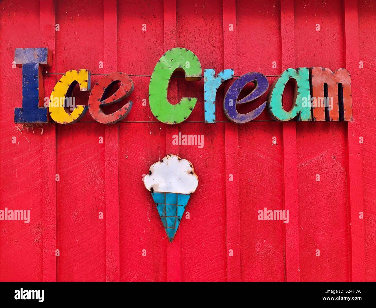 A brightly colored sign that says “ice cream” on a bright red wall Stock Photo