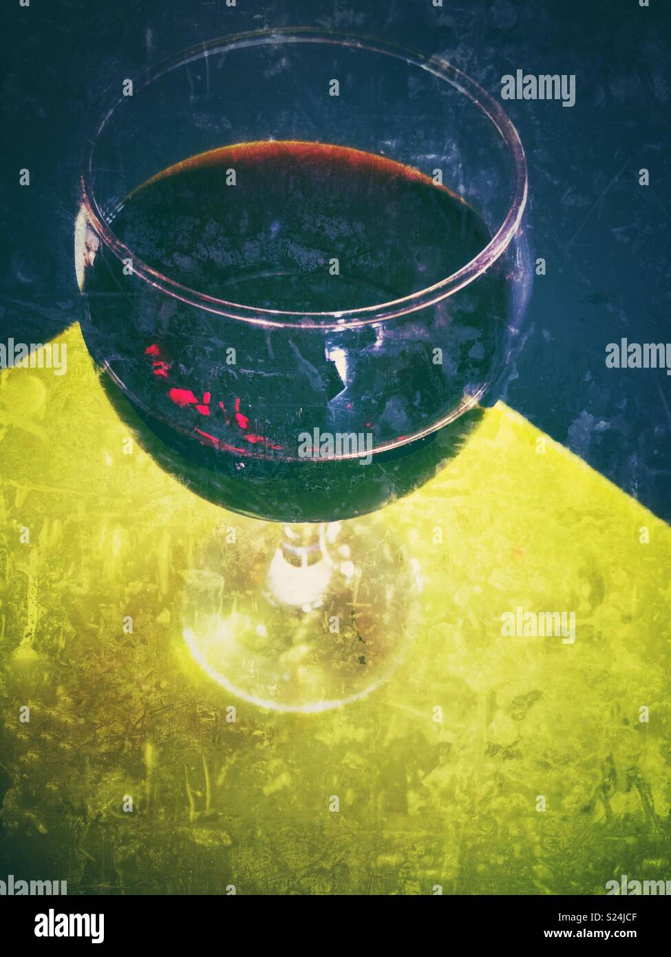 Glass of red wind on bright green surface with dark background and creative grunge processing - Smartphone Captured Stock Image