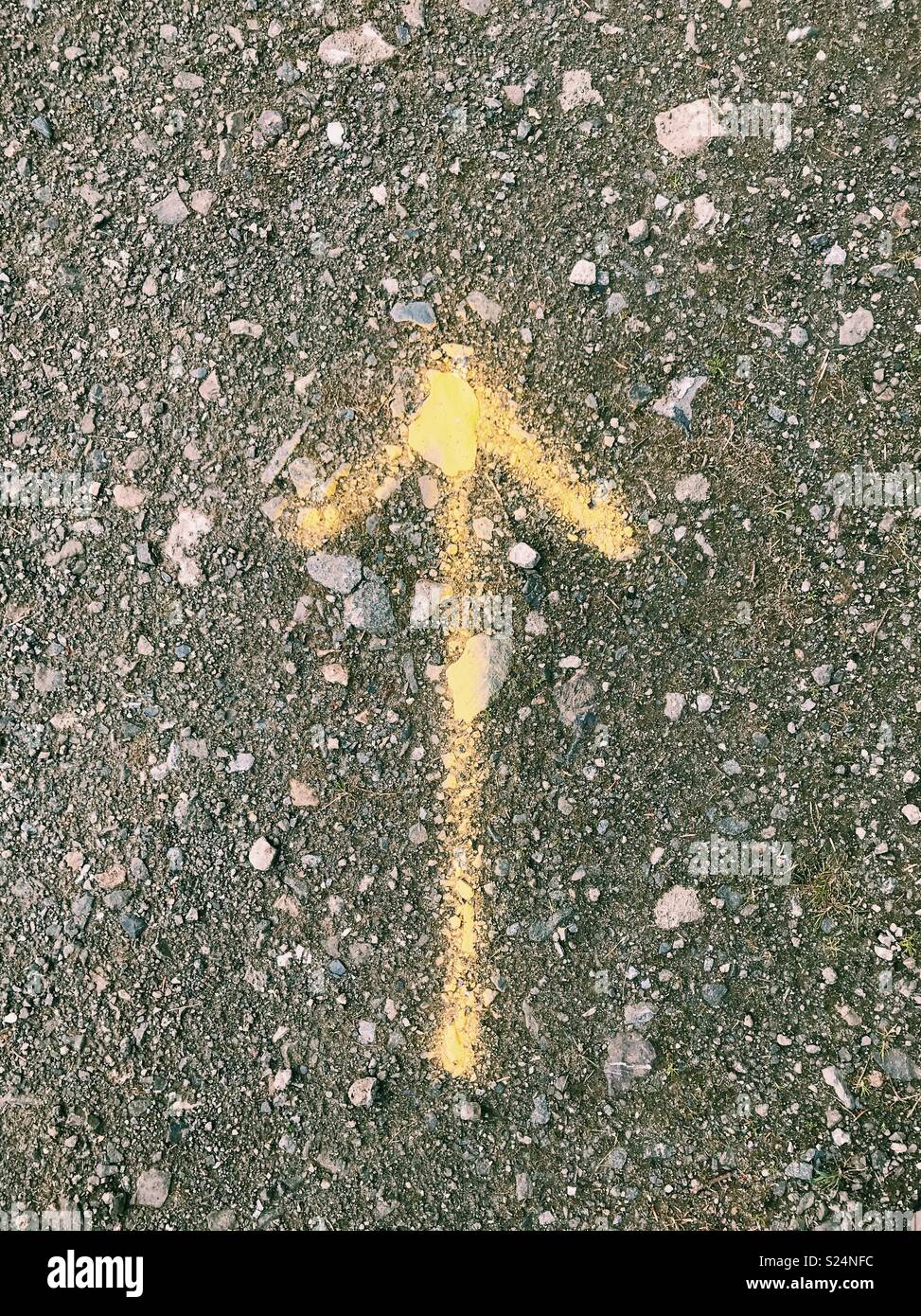 A yellow arrow sprayed on a dirt road in Northumberland, England. - Smartphone Captured Stock Image