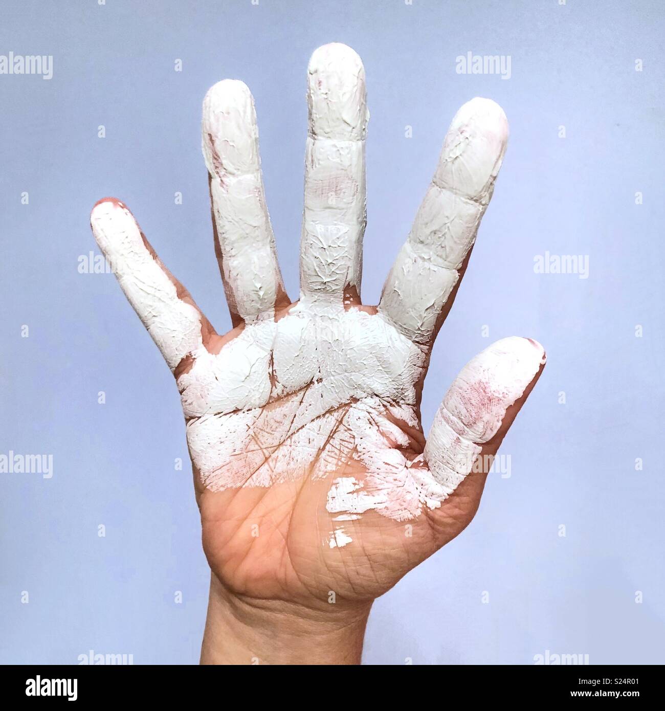 An outstretched hand covered in white paint - Smartphone Captured Stock Image