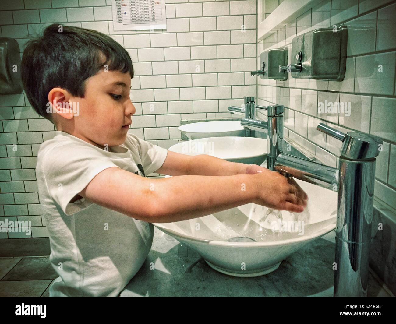 A young boy washes his hands at a sink in a public toilet Stock Photo Alamy