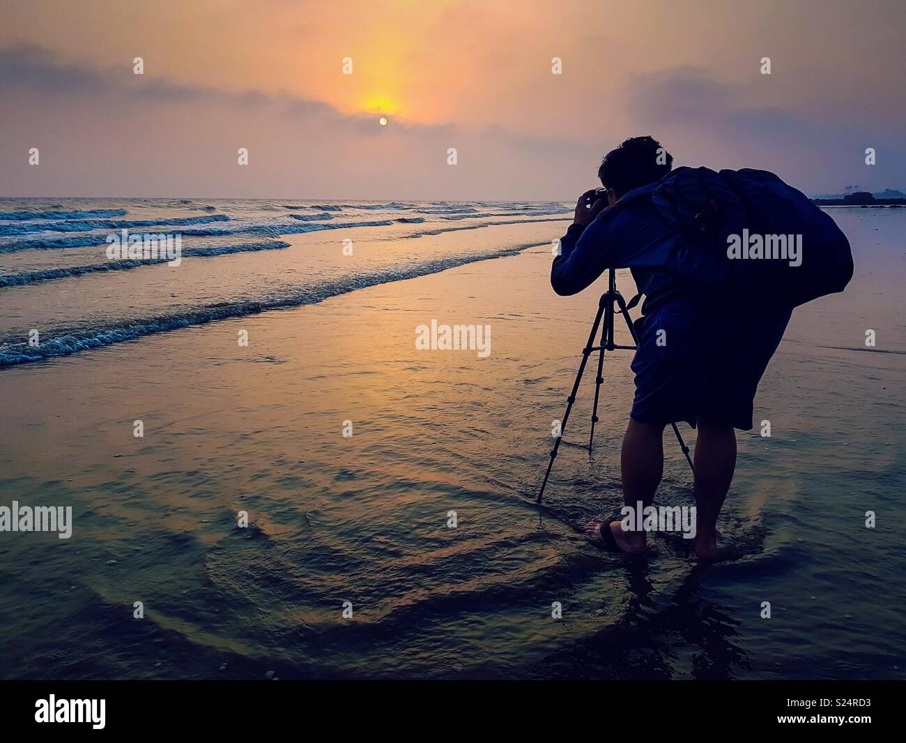 Photographer taking photos at sea beach during sunset Stock Photo
