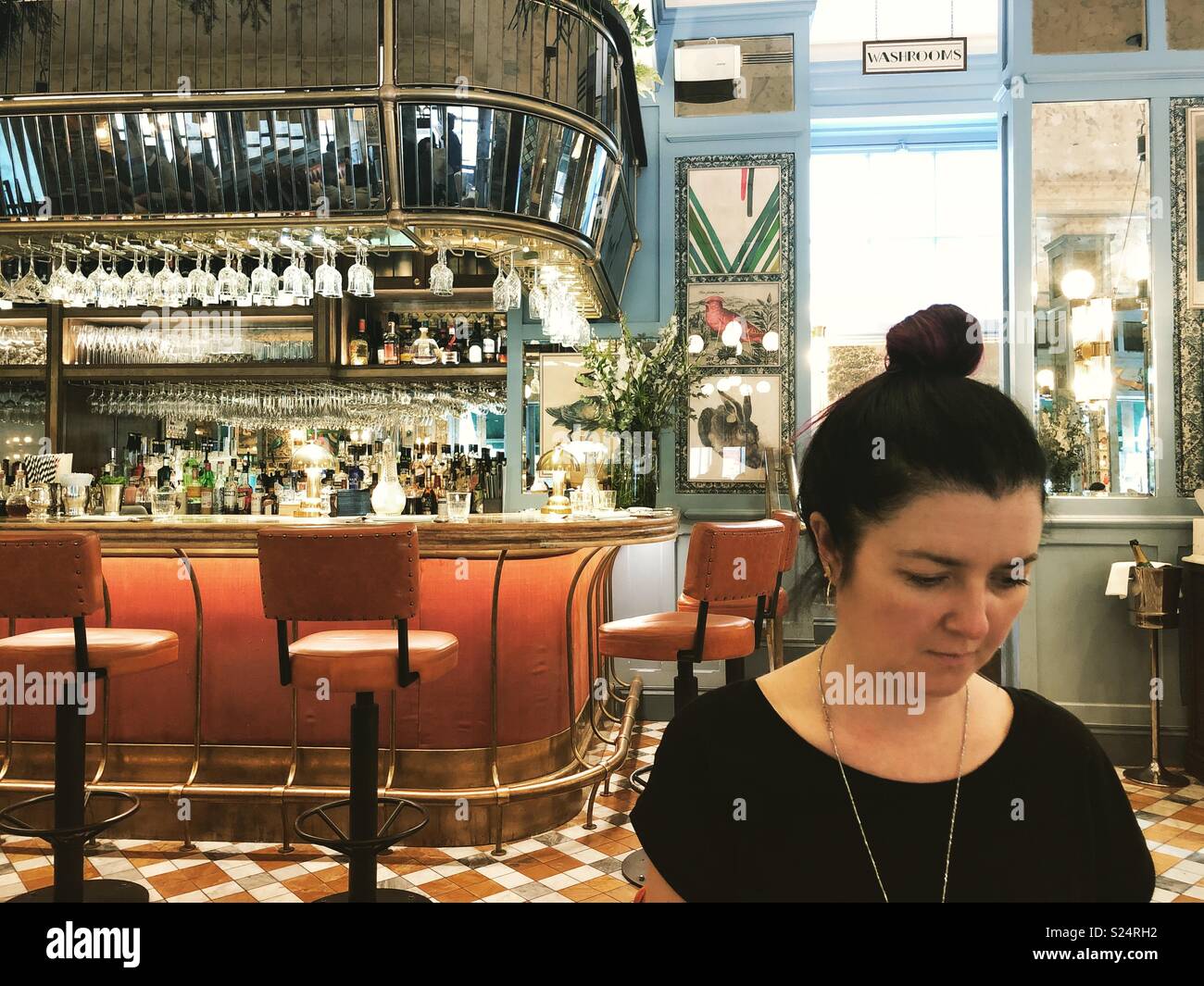 Brunette with top knot, wearing black in restaurant Stock Photo