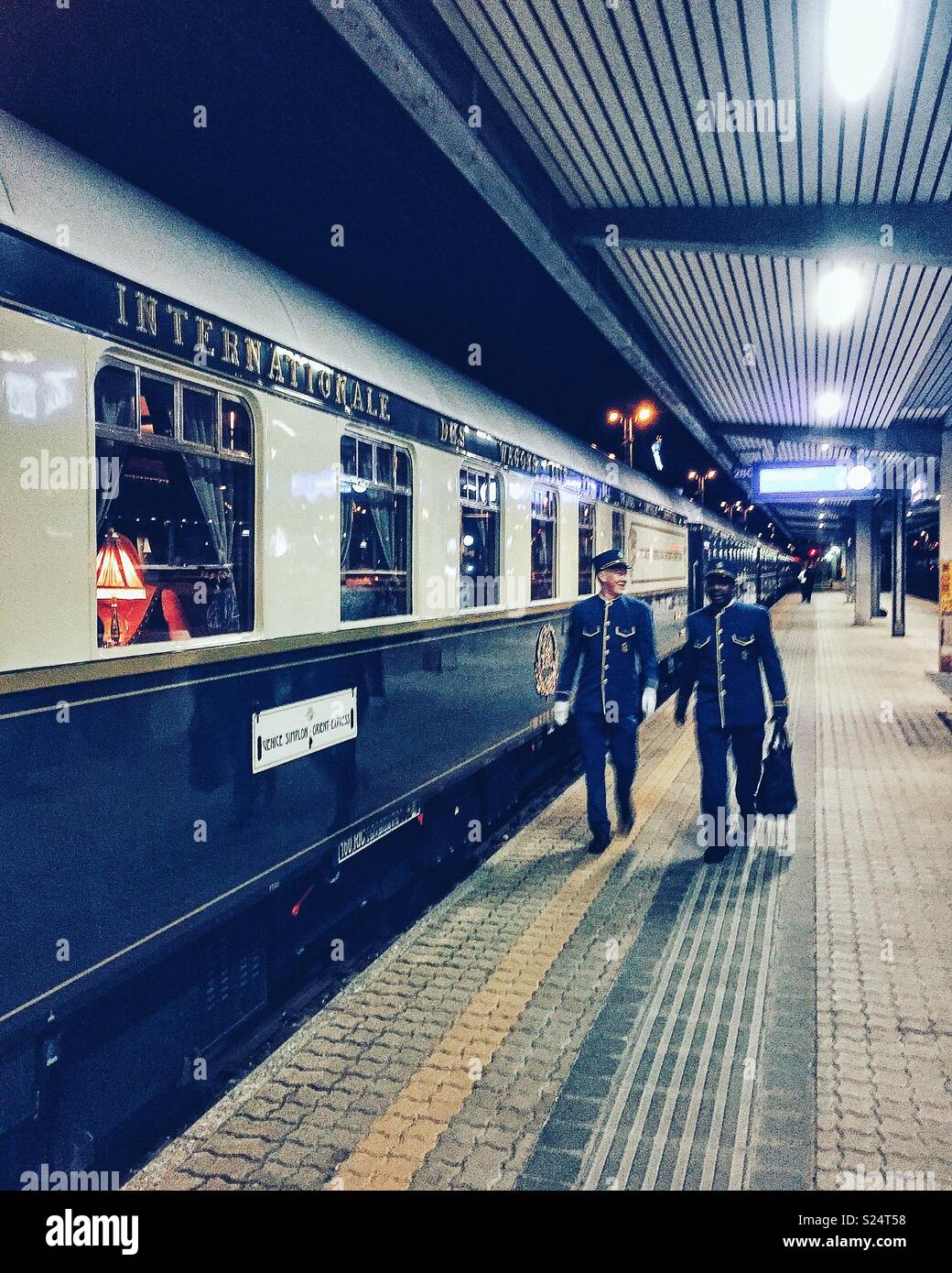 Orient Express carriage with two uniformed attendants striding by - Smartphone Captured Stock Image