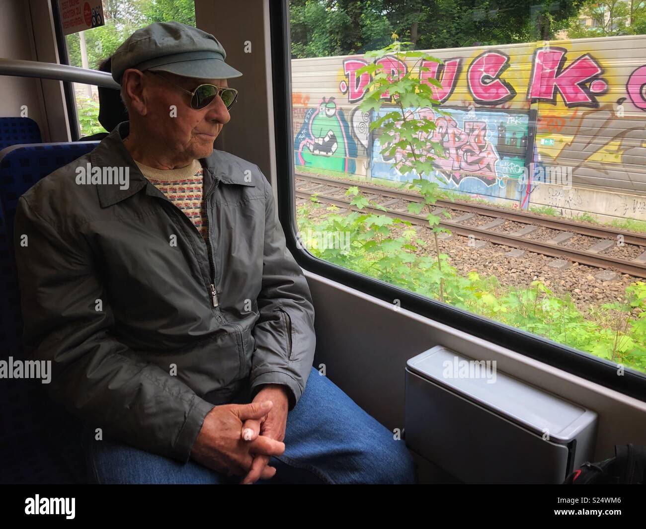 Elderly man sitting in a train looking out the window. - Smartphone Captured Stock Image