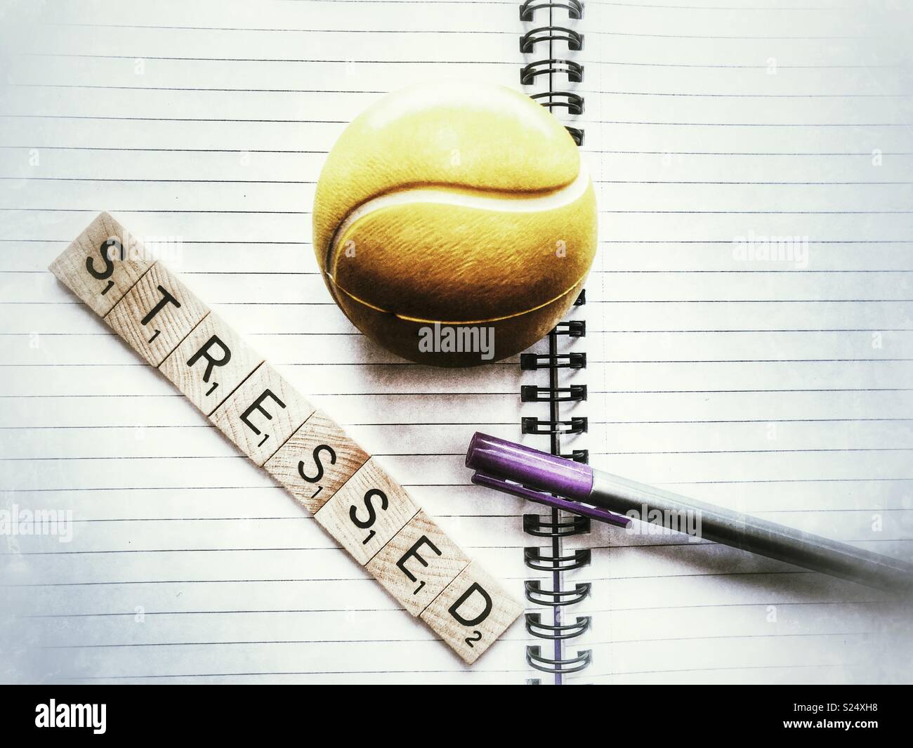 a stress ball, pen, and the word Stressed in wooden letters on an open, empty, spiral bound notebook Stock Photo