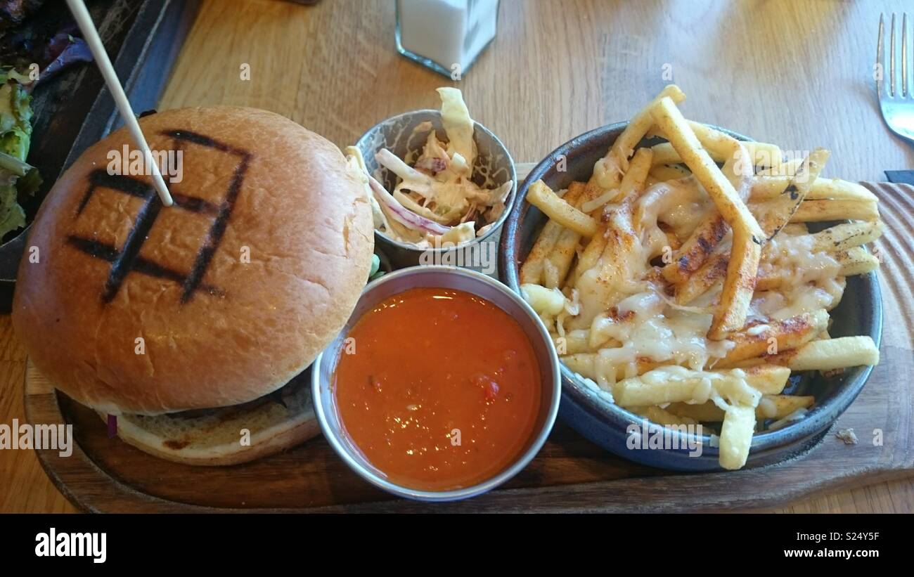 Beef burger and cheesy chips with sweet chilli sauce and coleslaw Stock Photo