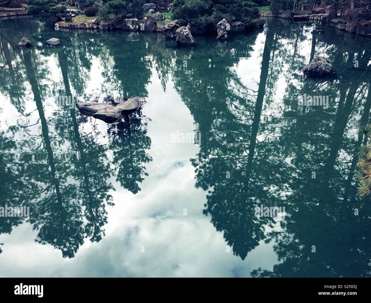 Calming water reflects tall trees in Nishinomiya Tsutakawa Japanese Garden, a place where nature, tranquility and beauty come together Stock Photo