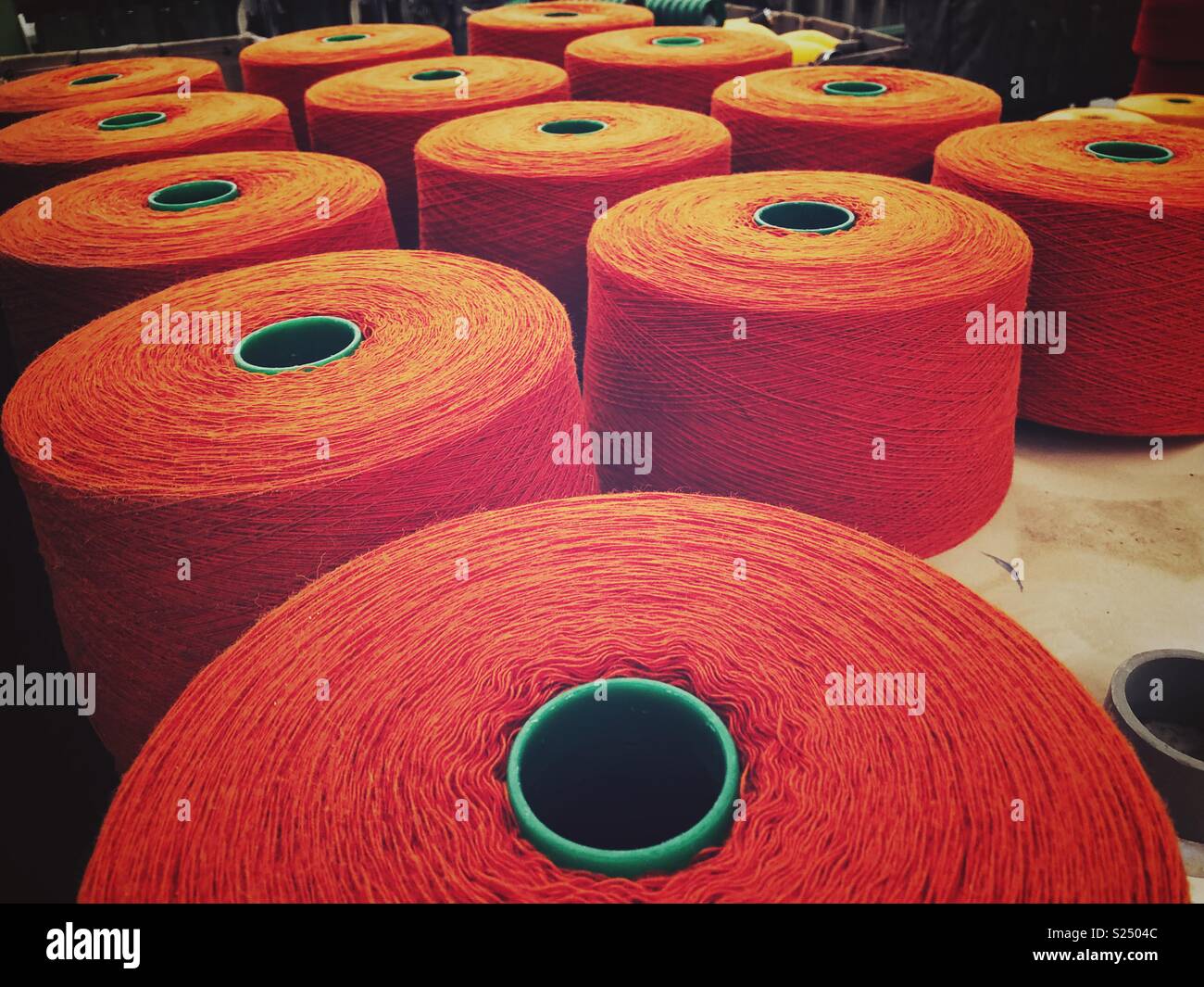 Bright orange yarn on industrial wool spools at Pendleton blanket factory in Oregon Stock Photo