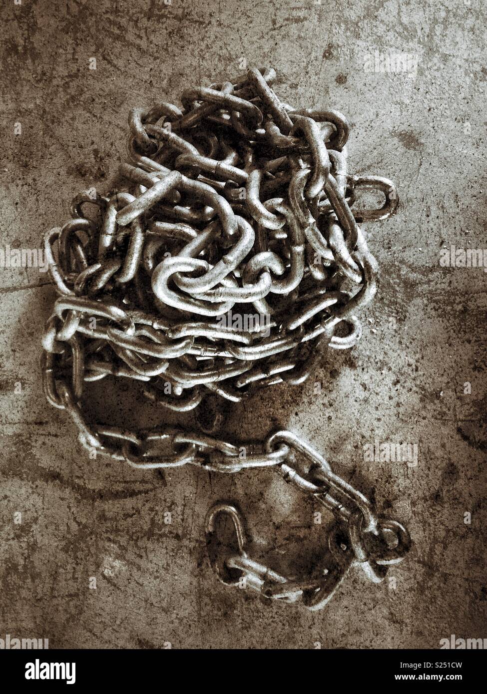 Long metal chain coiled in a heap on a concrete surface - Smartphone Captured Stock Image