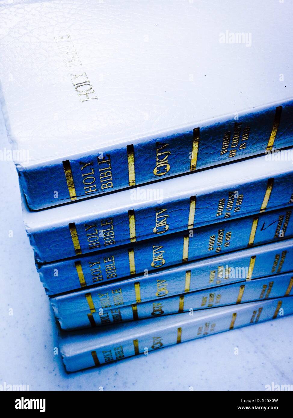 White background, stack of white Sunday School Bibles with blue shadow - Smartphone Captured Stock Image