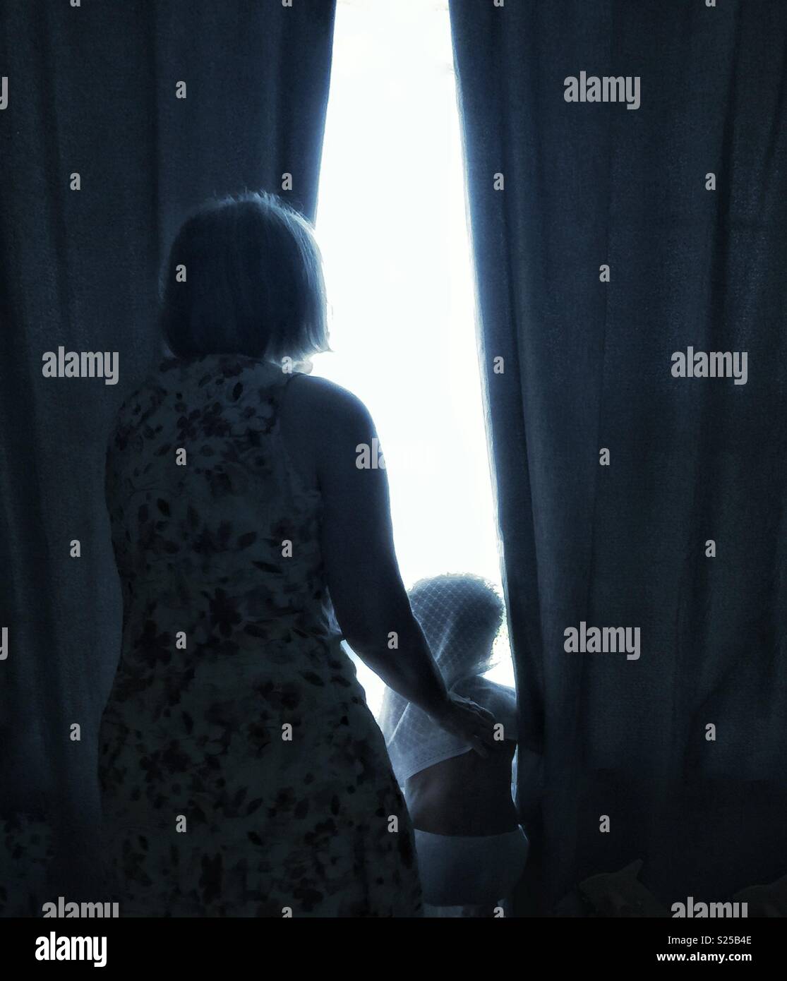 Family looking through a window in silhouette. Stock Photo