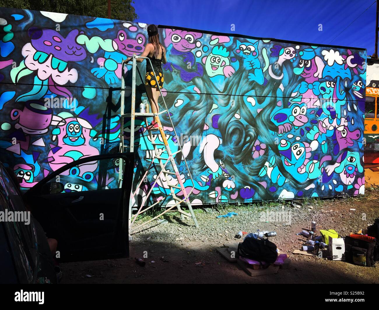 Woman graffiti artist paint spraying wall - Smartphone Captured Stock Image