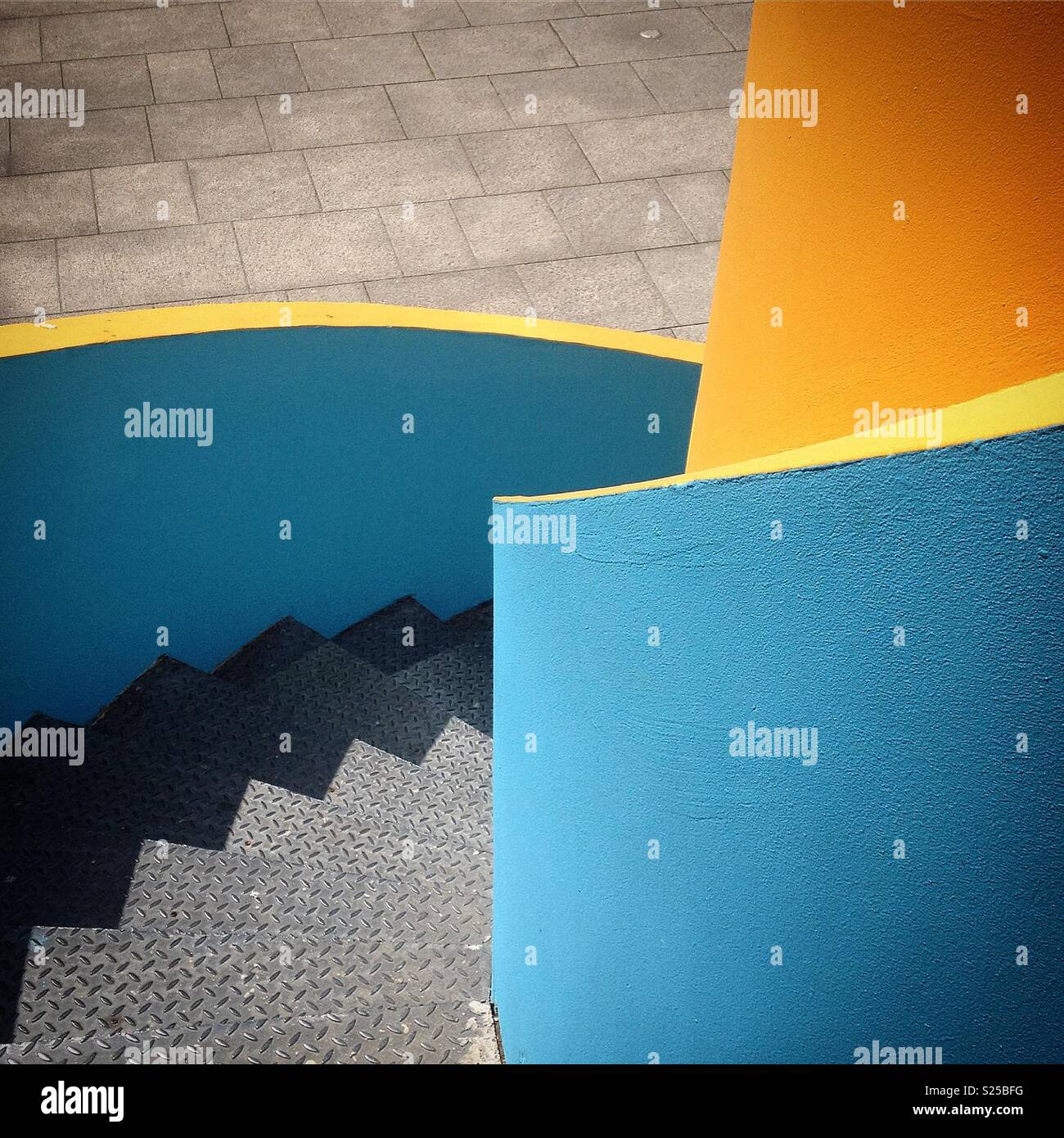 Metal steps with yellow and blue painted concrete wall Stock Photo