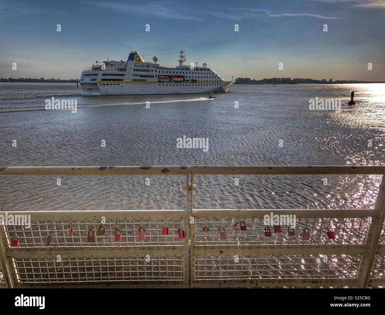 A cruise ship sails into the sunset on the Elbe River in Hamburg, Germany. - Smartphone Captured Stock Image