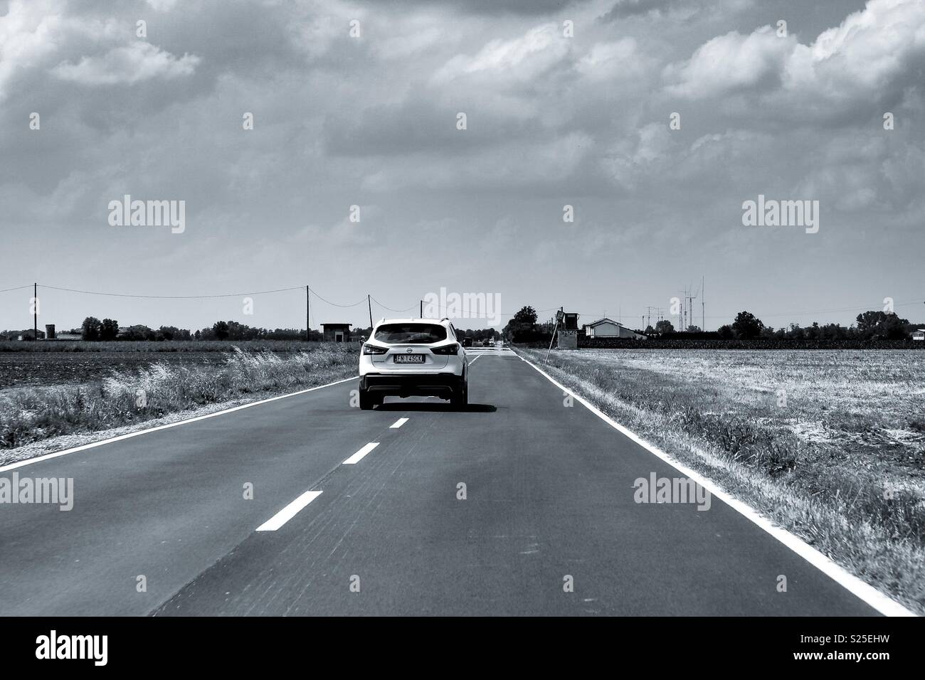 A white suv on a straight deserted country road - Smartphone Captured Stock Image